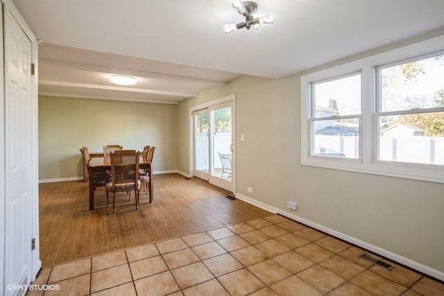 dining space with beam ceiling and light wood-type flooring