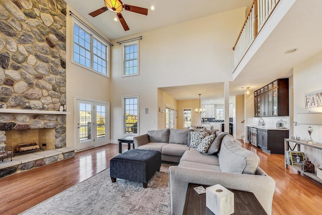 living room featuring ceiling fan with notable chandelier, light hardwood / wood-style floors, and a high ceiling