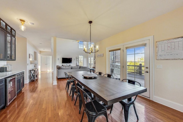 dining space with a chandelier, light hardwood / wood-style floors, and beverage cooler