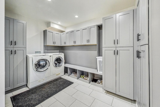 laundry area featuring separate washer and dryer, light tile patterned floors, and cabinets