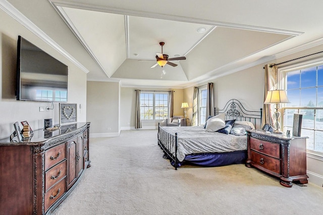 carpeted bedroom with a tray ceiling, ceiling fan, and crown molding