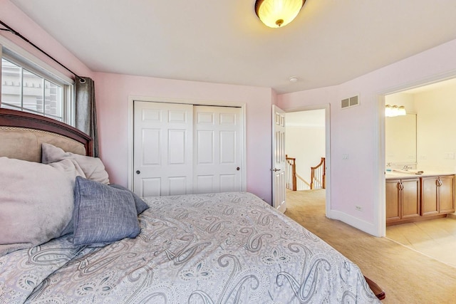 bedroom with ensuite bathroom, a closet, and light colored carpet