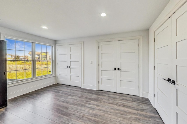 unfurnished bedroom featuring two closets and dark wood-type flooring