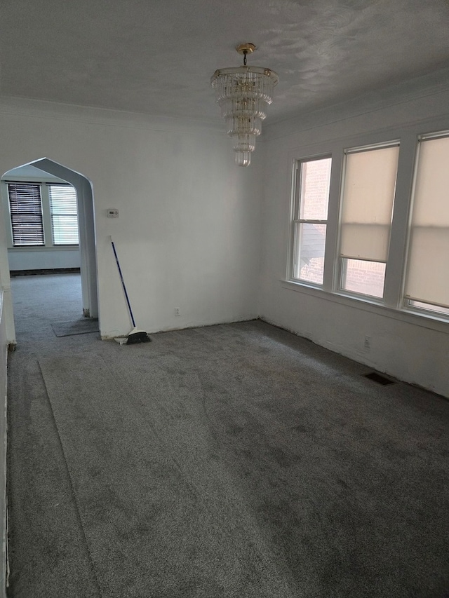 unfurnished room with a notable chandelier, a textured ceiling, and carpet floors