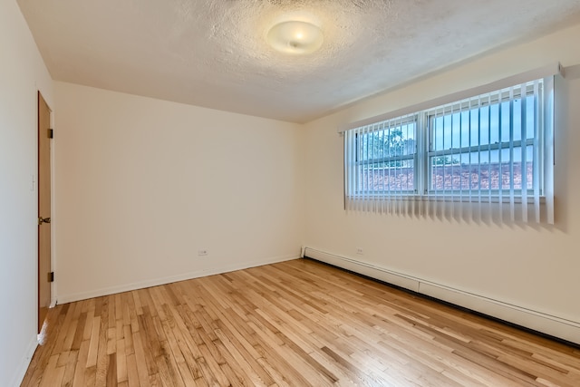 spare room with light hardwood / wood-style flooring, a textured ceiling, and baseboard heating