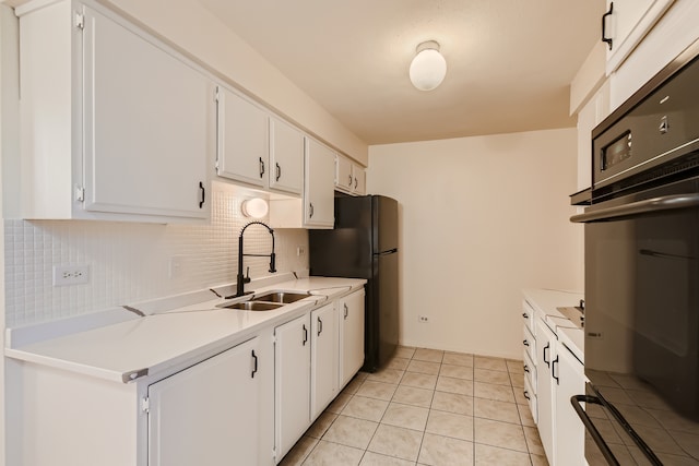 kitchen with white cabinetry, black appliances, sink, light tile floors, and tasteful backsplash