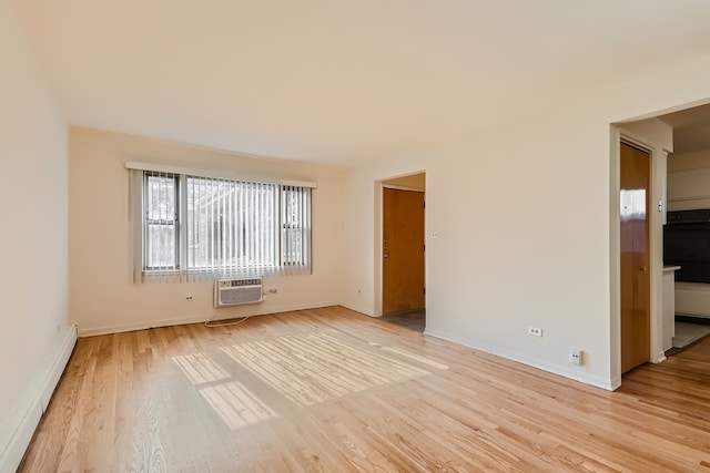 spare room featuring a wall mounted air conditioner, light hardwood / wood-style floors, and baseboard heating