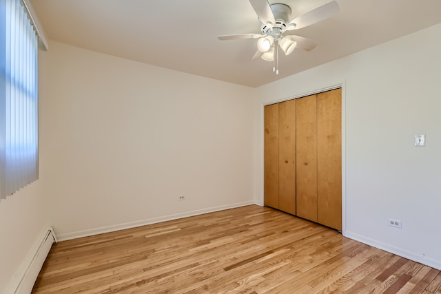 unfurnished bedroom with ceiling fan, baseboard heating, light hardwood / wood-style floors, and a closet