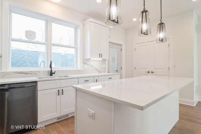 kitchen with a kitchen island, white cabinets, stainless steel dishwasher, and light wood-type flooring