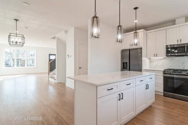 kitchen with decorative light fixtures, light hardwood / wood-style flooring, stainless steel appliances, a kitchen island, and tasteful backsplash