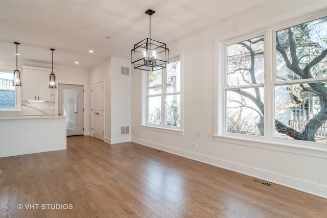 unfurnished dining area featuring hardwood / wood-style flooring and an inviting chandelier