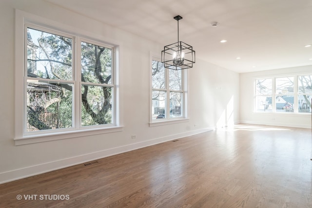 unfurnished room featuring hardwood / wood-style floors, plenty of natural light, and a chandelier