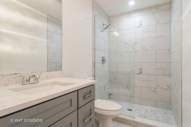 bathroom with tiled shower, vanity, and toilet