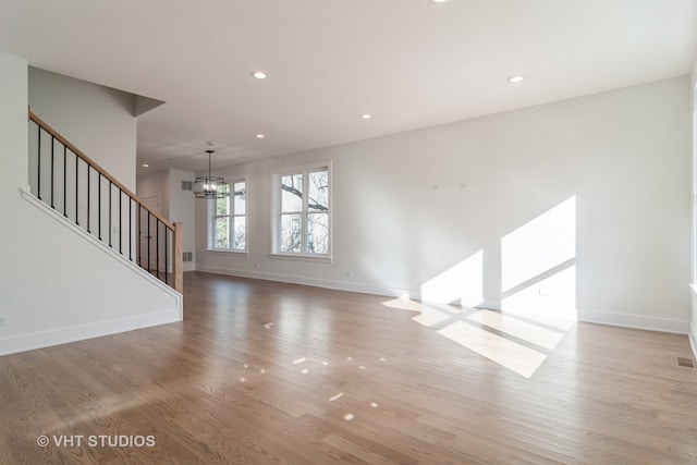 spare room with a notable chandelier and light hardwood / wood-style floors