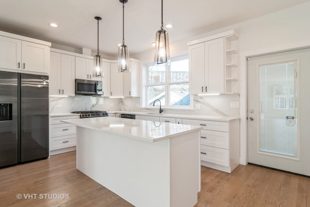 kitchen featuring hanging light fixtures, light hardwood / wood-style floors, a center island, and stainless steel appliances