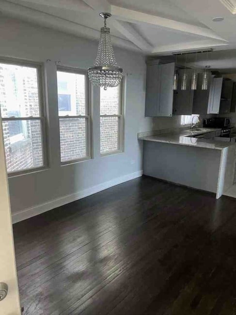 kitchen featuring a notable chandelier, kitchen peninsula, gray cabinets, dark wood-type flooring, and hanging light fixtures