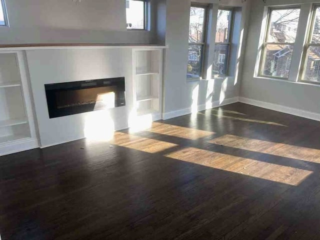 unfurnished living room featuring dark hardwood / wood-style floors and built in features