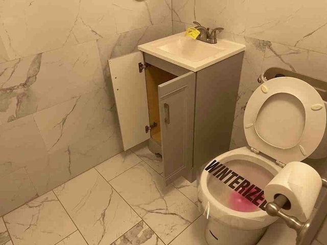 bathroom featuring tile flooring, toilet, vanity, and tile walls