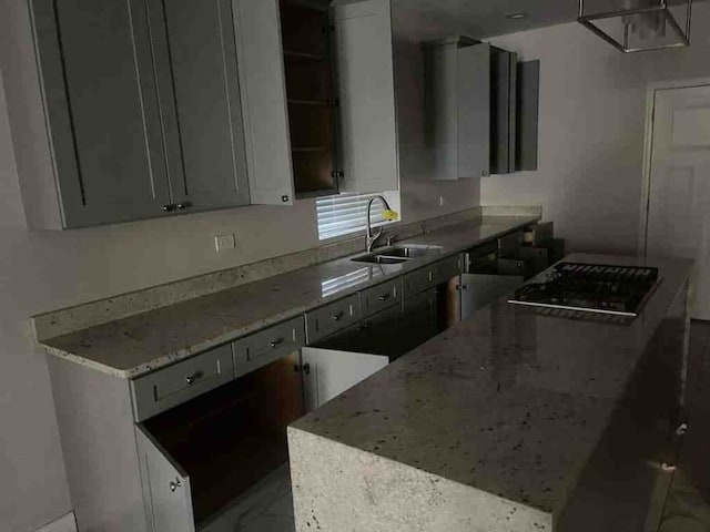 kitchen featuring black electric stovetop, gray cabinetry, a center island, light stone countertops, and sink