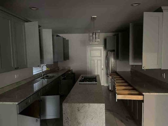 kitchen featuring sink, gray cabinets, a kitchen island, and decorative light fixtures