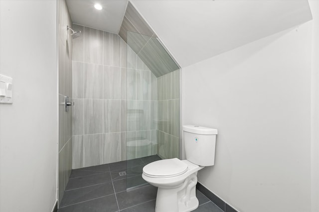 bathroom featuring toilet, tiled shower, and tile flooring