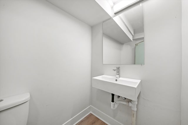 bathroom with toilet, sink, and hardwood / wood-style flooring