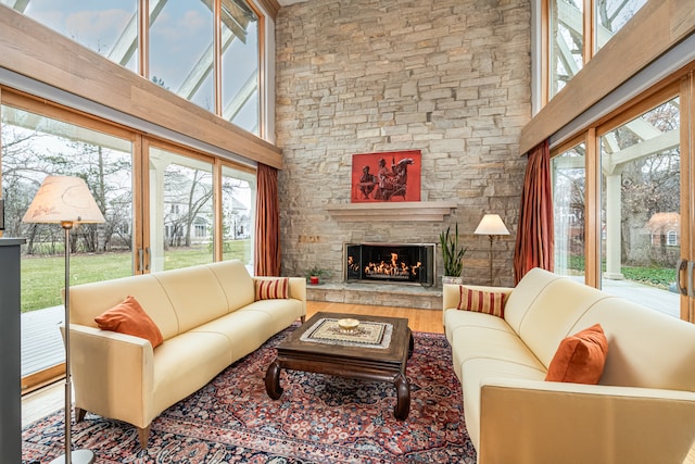 living room featuring a high ceiling, a stone fireplace, and hardwood / wood-style flooring