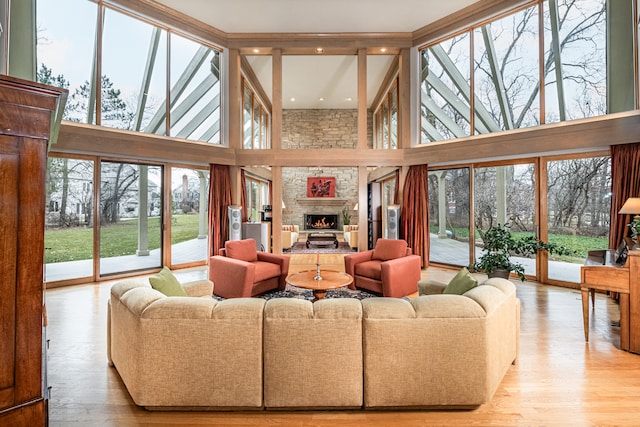 living room with light hardwood / wood-style flooring, a large fireplace, and a high ceiling