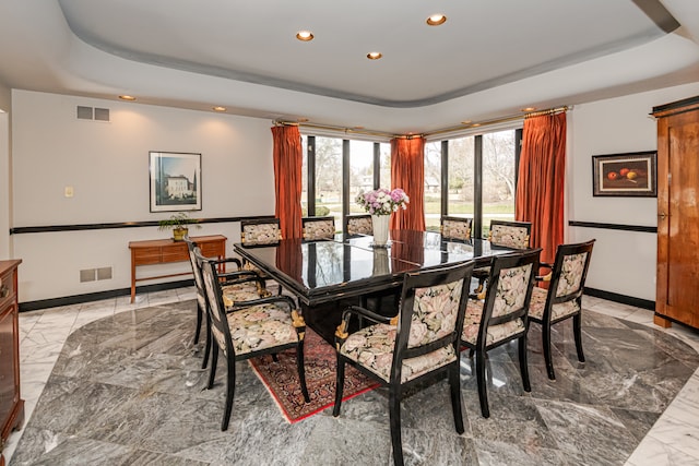 dining area featuring light tile patterned floors and a raised ceiling