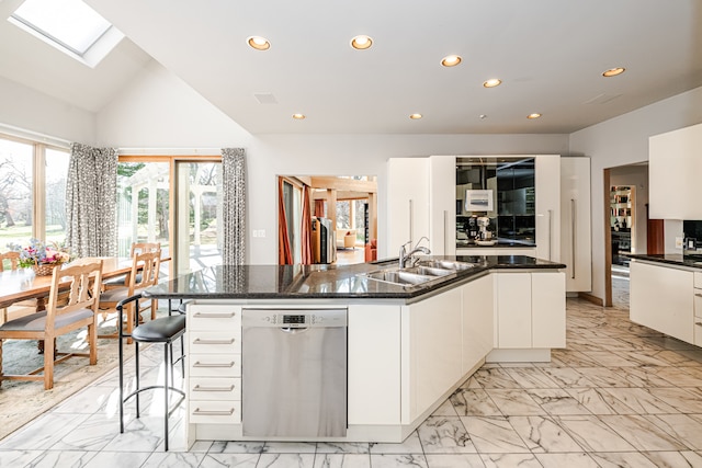 kitchen featuring a skylight, a kitchen island with sink, dishwasher, and light tile patterned floors