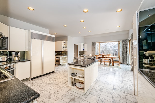 kitchen featuring light tile patterned flooring, paneled refrigerator, a center island, and white cabinets