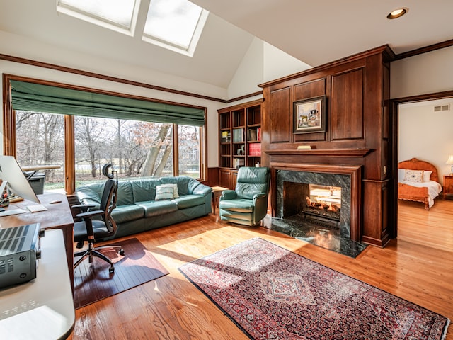 office featuring a fireplace, lofted ceiling, crown molding, and light wood-type flooring