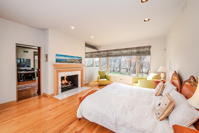 bedroom with a premium fireplace and light hardwood / wood-style flooring