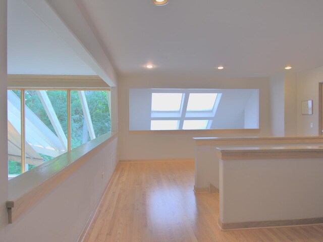 hallway featuring a skylight and light wood-type flooring