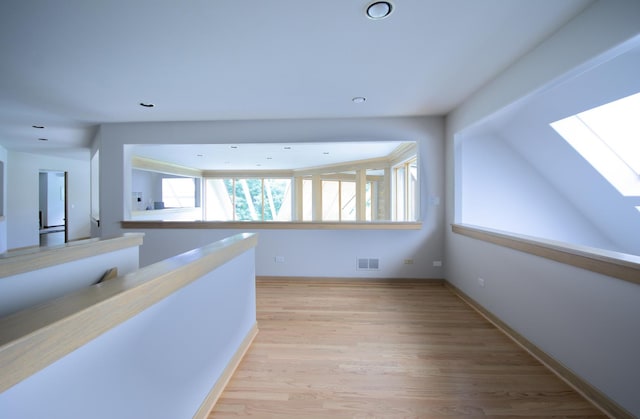 corridor with light hardwood / wood-style flooring and a skylight