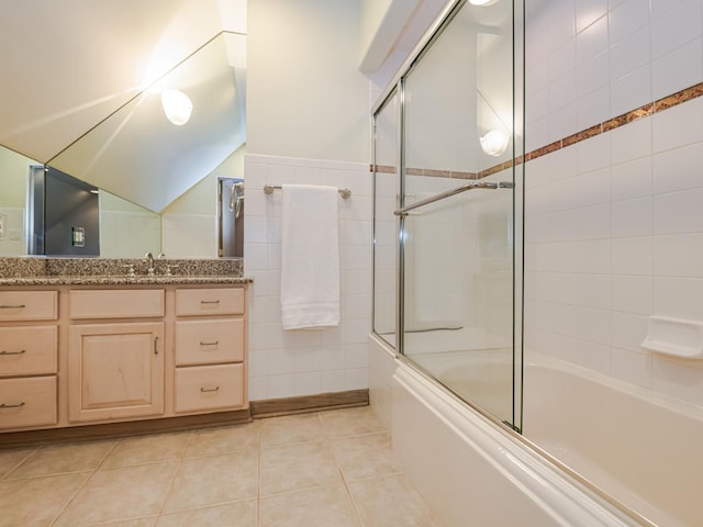 bathroom with tile walls, shower / bath combination with glass door, vanity, and tile patterned flooring