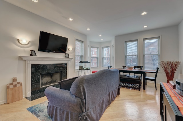 living room featuring light wood-type flooring and a tiled fireplace