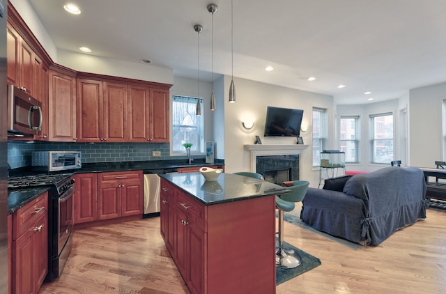 kitchen featuring light wood-type flooring, hanging light fixtures, a center island, and appliances with stainless steel finishes