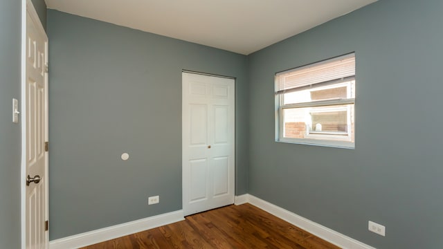 unfurnished bedroom featuring a closet and dark wood-type flooring