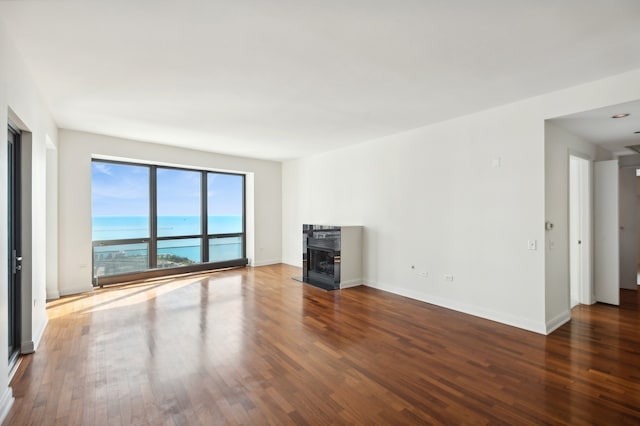 unfurnished living room featuring dark hardwood / wood-style flooring and a water view