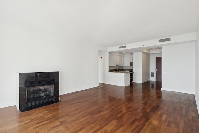 unfurnished living room featuring dark hardwood / wood-style flooring and a tiled fireplace