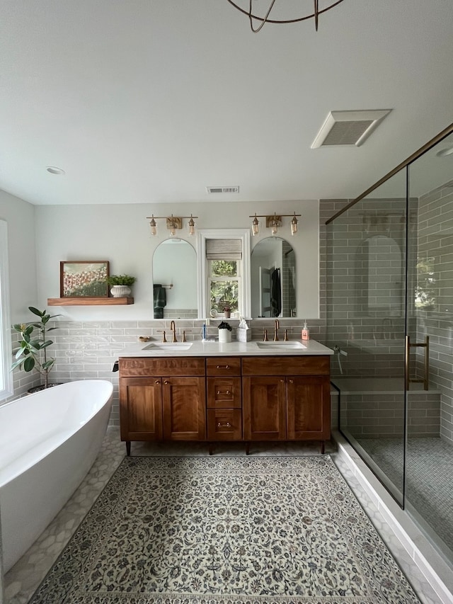 bathroom with tile walls, double vanity, shower with separate bathtub, and tile flooring