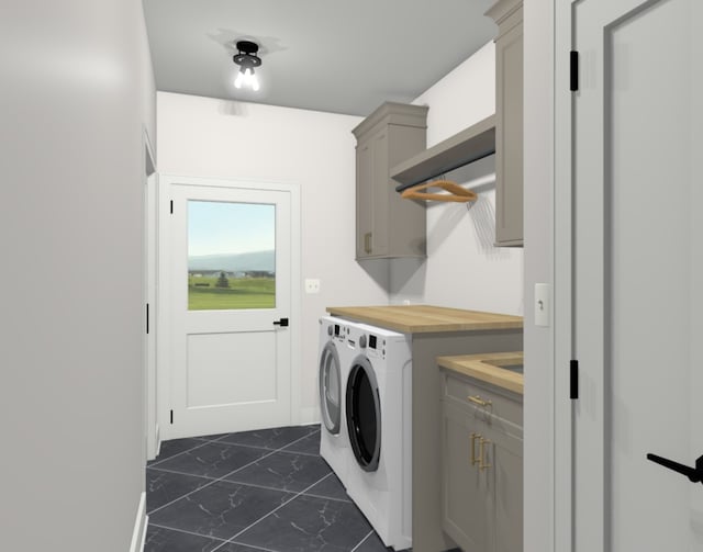 washroom featuring dark tile flooring, washer and dryer, and cabinets