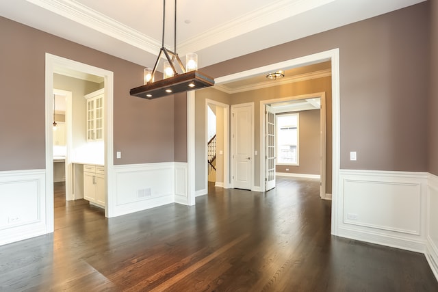 unfurnished dining area with an inviting chandelier, dark wood-type flooring, and crown molding