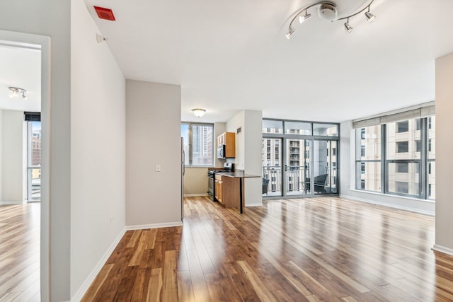 unfurnished living room with rail lighting and light hardwood / wood-style floors