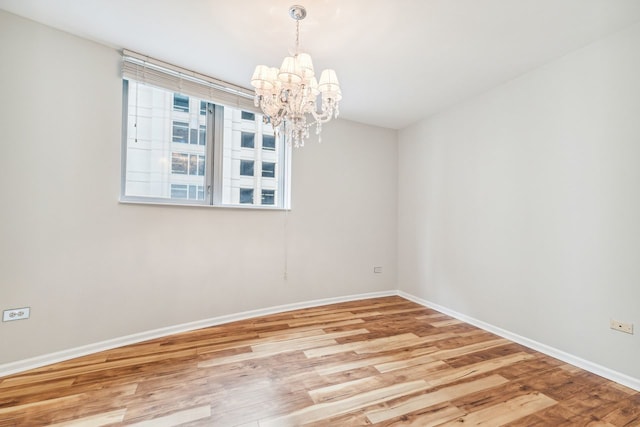 spare room with light hardwood / wood-style floors and a chandelier