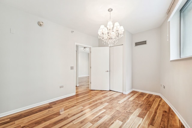 unfurnished room with an inviting chandelier and light hardwood / wood-style floors