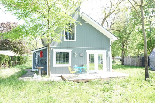 rear view of house with a wooden deck, a yard, and french doors