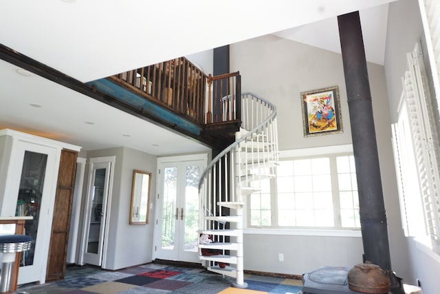 foyer entrance featuring french doors, a towering ceiling, and a wood stove