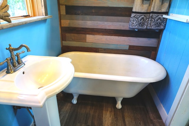 bathroom featuring hardwood / wood-style flooring, sink, a bathtub, and wood walls